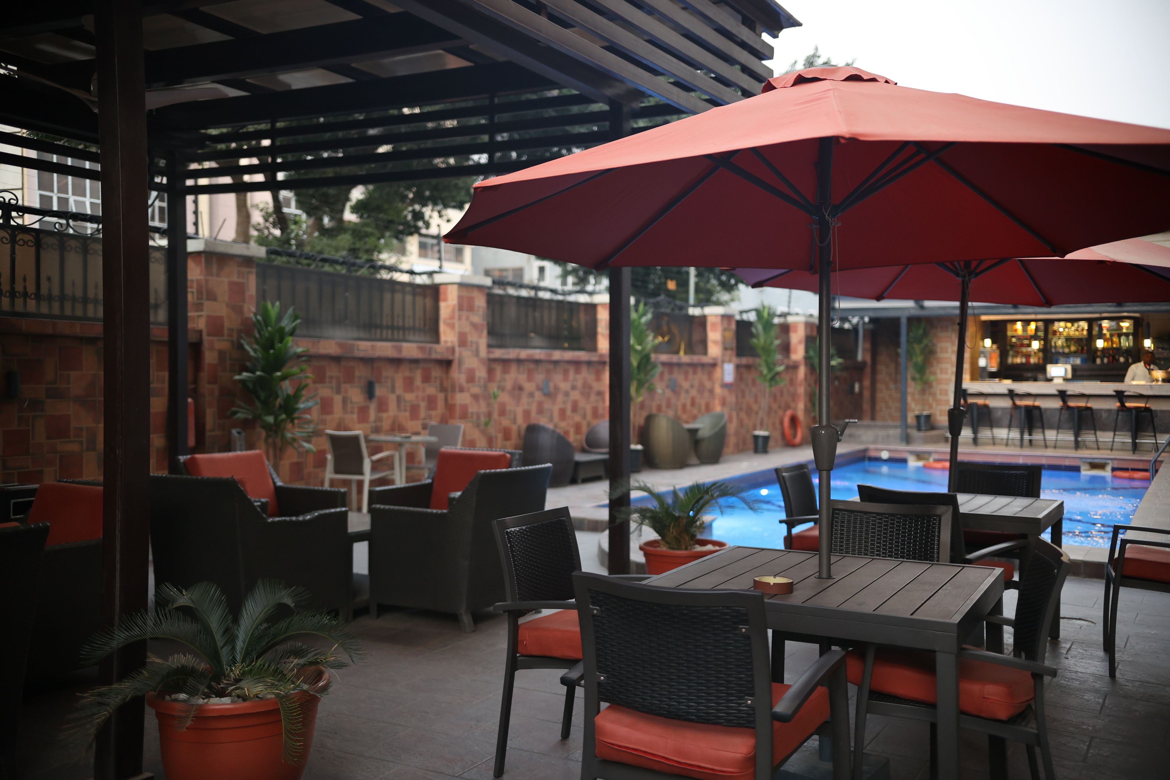 An outdoor patio with tables and chairs, a pool, and a bar area.