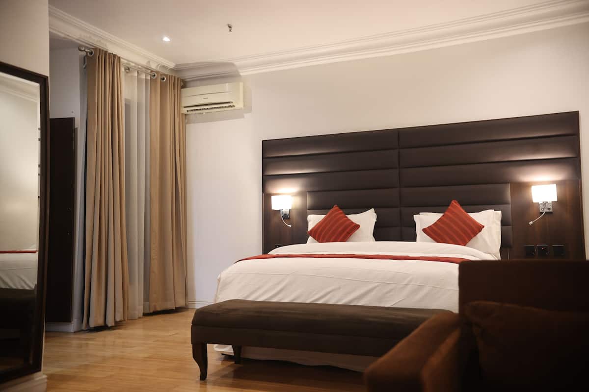 Ein Hotelzimmer mit einem großen Bett, zwei Nachttischlampen, einer Klimaanlage und Holzboden.