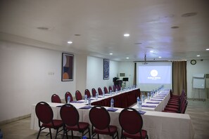 A conference room with a long table, red chairs, water bottles, and a projector screen displaying 'Bolton White'. - Bolton White Hotel - Abuja (Abuja)