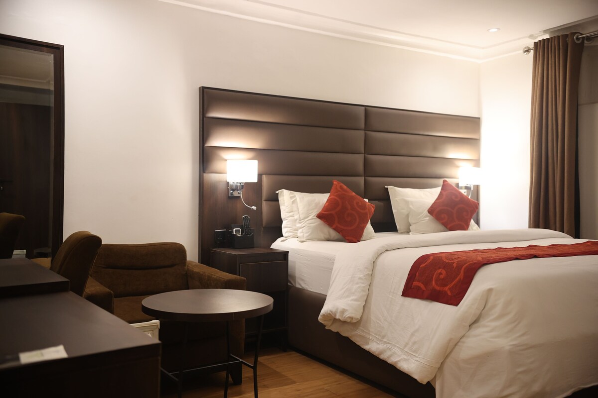 Une chambre d’hôtel avec un grand lit, une table de chevet, une chaise et une petite table ronde.
