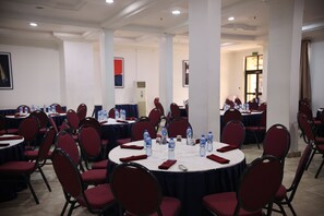 A conference room with round tables, red chairs, water bottles, and red napkins. - Bolton White Hotel - Abuja (Abuja)