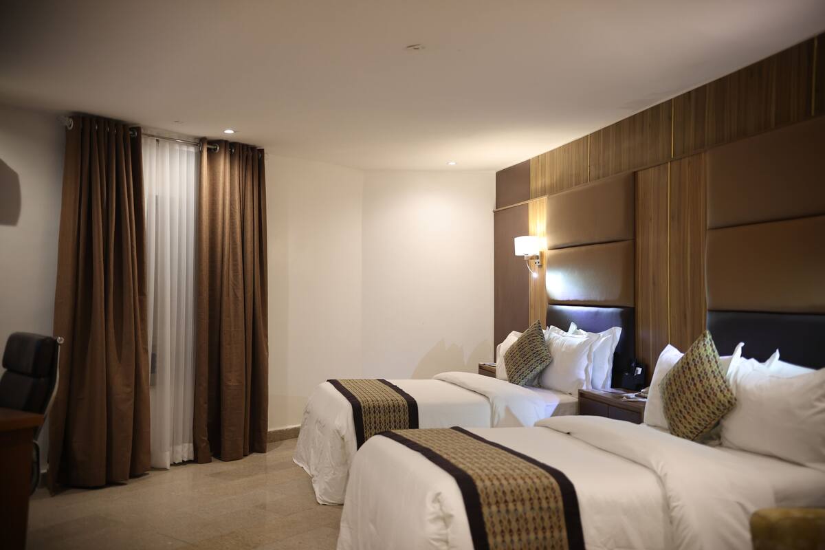 Ein Hotelzimmer mit zwei Betten, einem Schreibtisch und einem Stuhl.