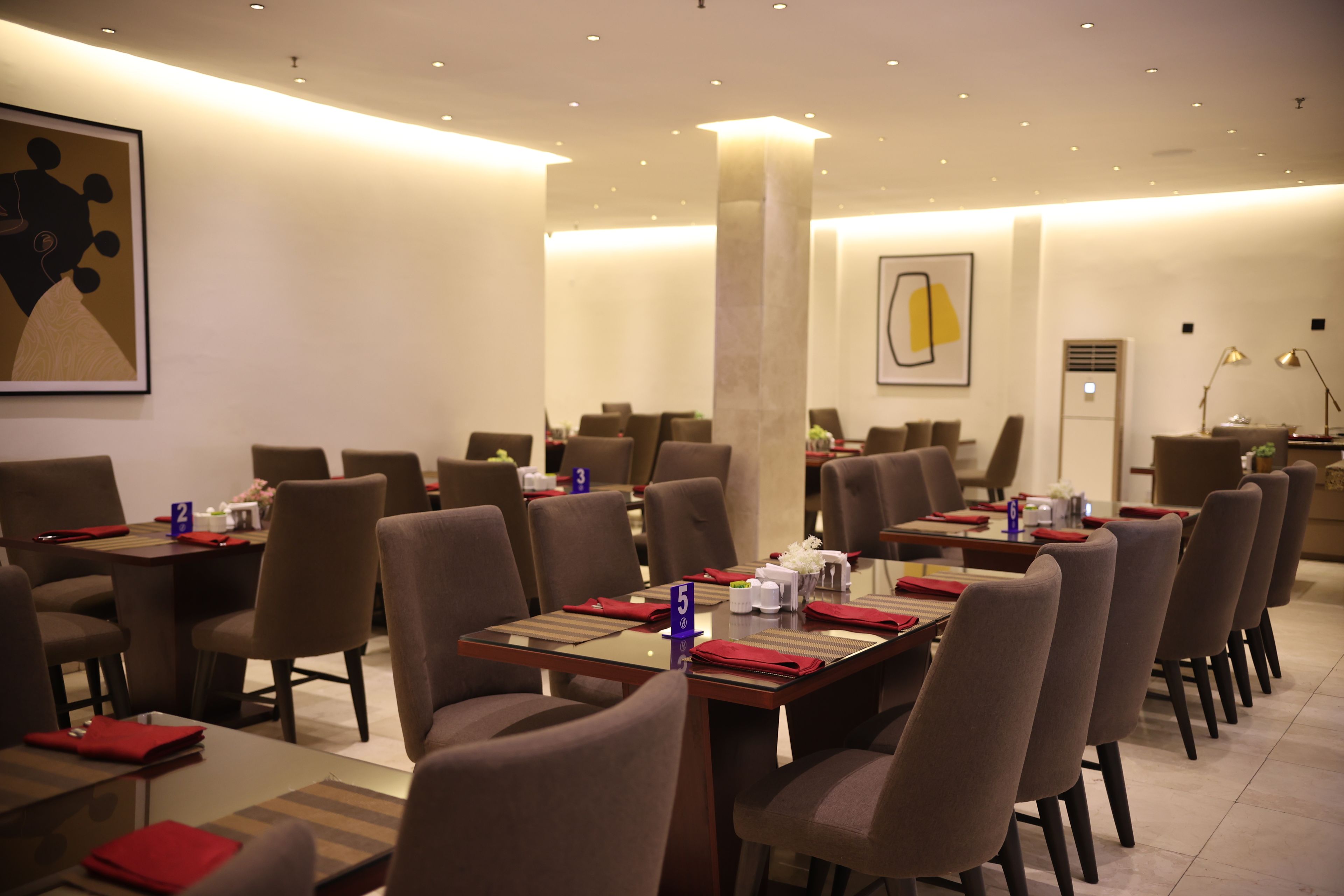 A restaurant with multiple tables and chairs, numbered placemats, and a modern interior design.