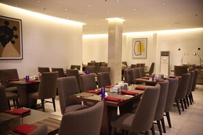 A restaurant with multiple tables and chairs, numbered placemats, and a modern interior design. - Bolton White Hotel - Abuja (Abuja)