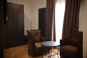 Une pièce comprenant deux fauteuils marron, une petite table ronde et une armoire.
