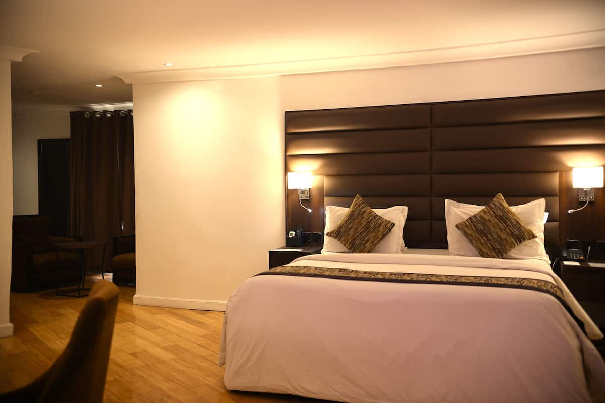 Ein Hotelzimmer mit einem großen Bett, zwei Nachttischen mit Lampen, einem dunklen Kopfteil und einem Holzboden.