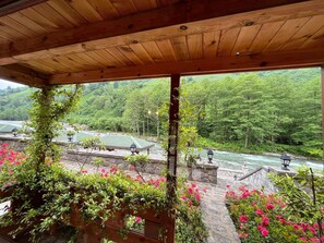 Puinen pergola, josta avautuu näkymä joelle ja vehreälle kasvillisuudelle.