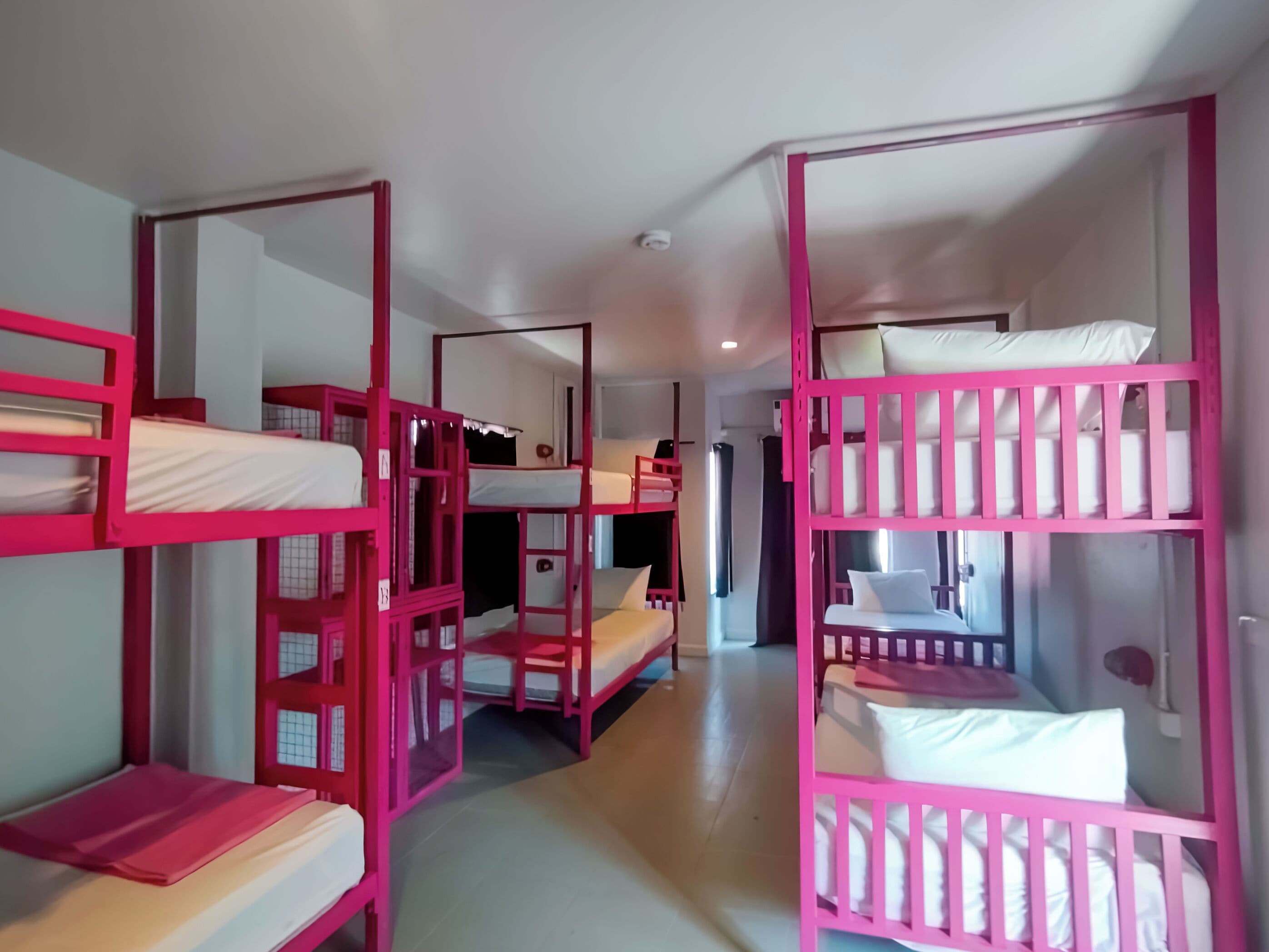 A room with bunk beds arranged in a row, a door, and a window.