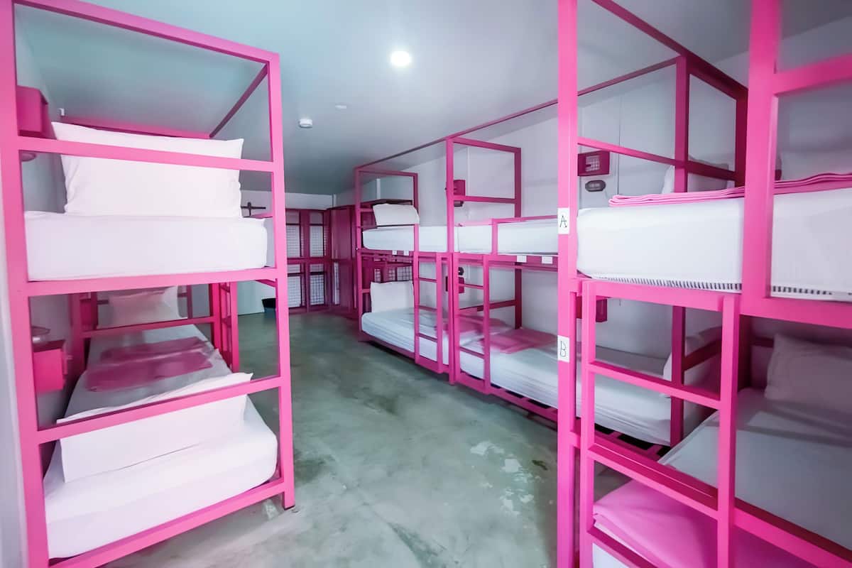 Beliches com estrutura rosa em um quarto tipo dormitório.