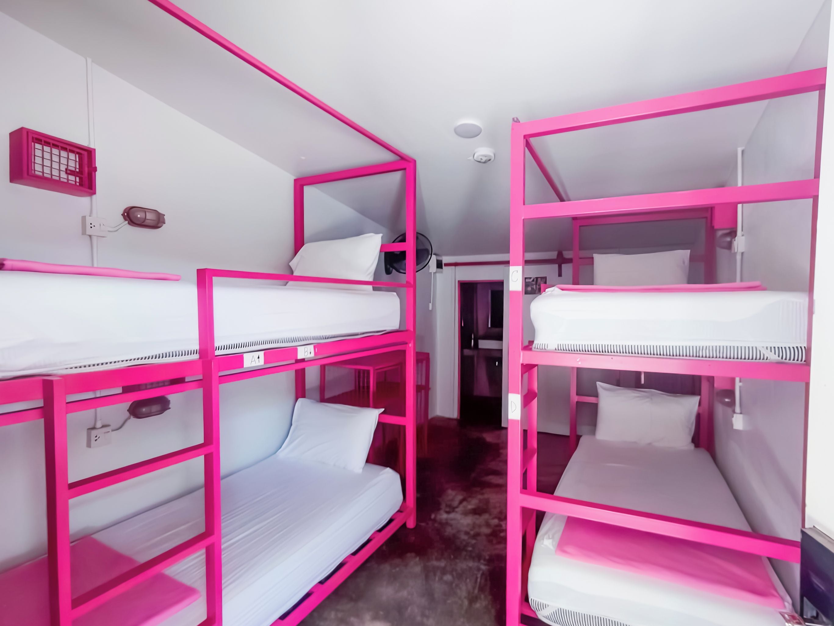 A room with bunk beds, a power outlet, and a ceiling fan.