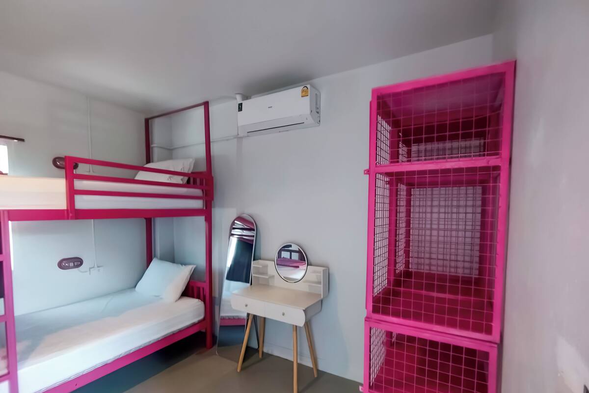 Quarto com beliche, escrivaninha e armários cor-de-rosa.