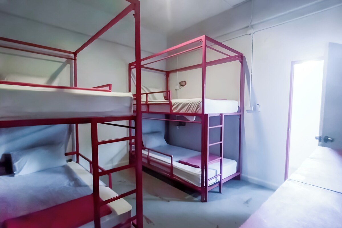 Ein Schlafsaalzimmer mit Etagenbetten, einer Tür und einer Wandleuchte.