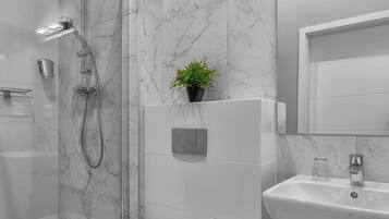 A modern bathroom with a glass-enclosed shower, a toilet, a sink, and a marble-tiled wall.
