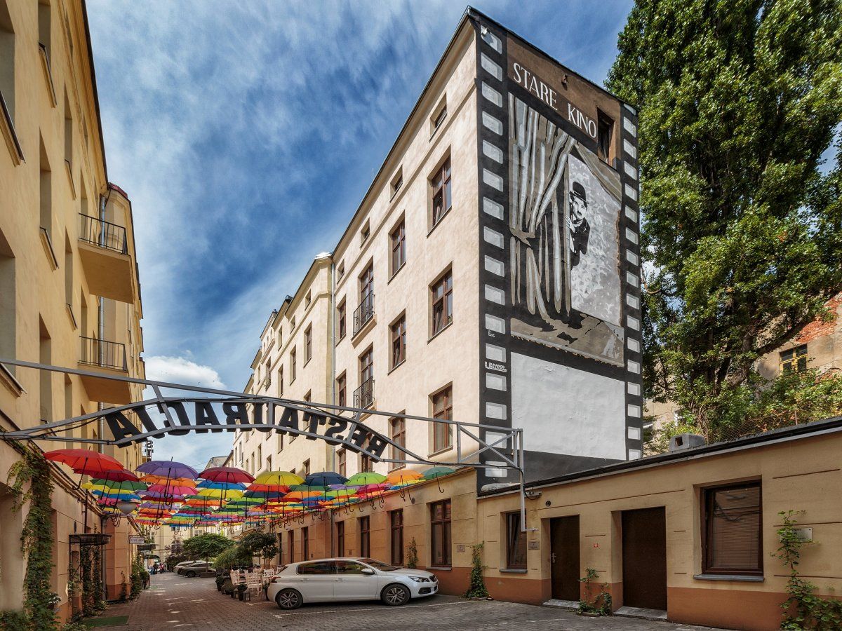 Un edificio con un cartel grande que dice 'STARE KINO' y un arco de entrada con sombrillas de colores.