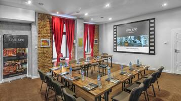 A conference room with a long table, chairs, and a projector screen.