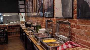 A buffet setup with various food items, a brick wall, and framed pictures.