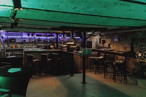 Uma área de bar com banquetas, um balcão e uma placa com a inscrição 'STARE KINO'.