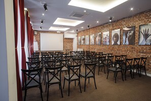 A conference room with rows of chairs, a whiteboard, and a brick wall with posters. - Cinema Rooms - Piotrkowska (Łódź)