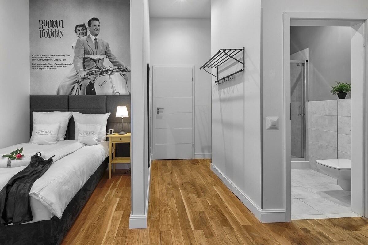 Ein modernes Hotelzimmer mit Bett, Nachttisch, Wand-Fernseher und Duschbereich.