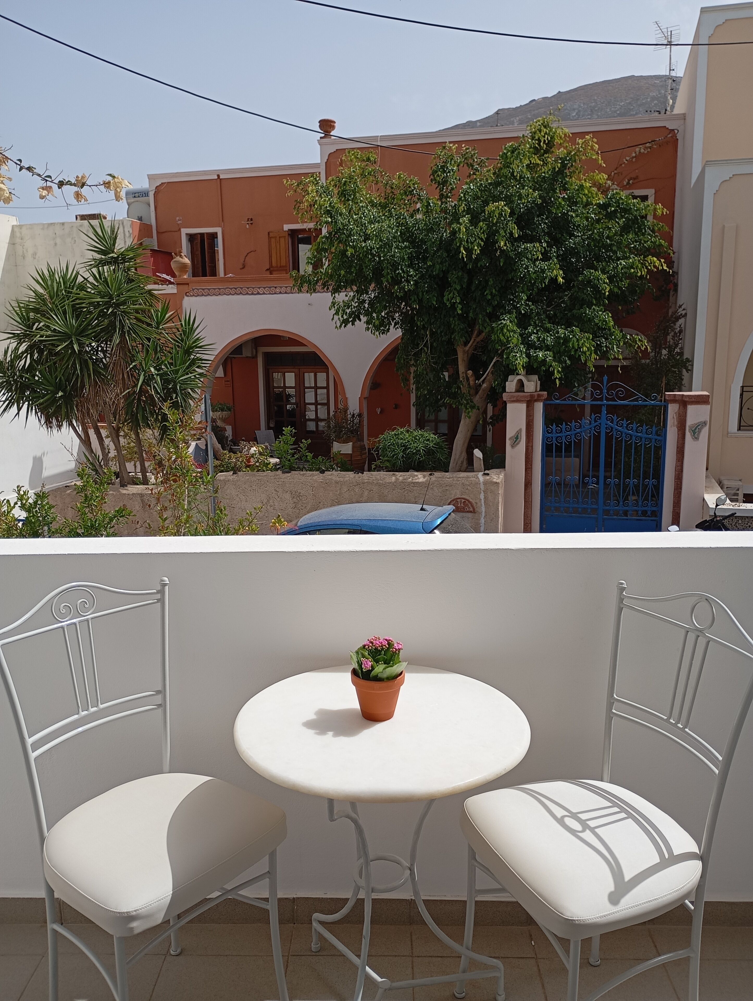 Ein Balkon mit zwei weißen Stühlen, einem kleinen runden Tisch und einem Blumentopf.