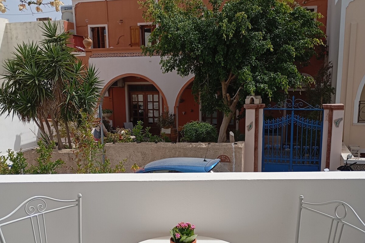 A balcony with two white chairs, a small round table, and a potted plant.