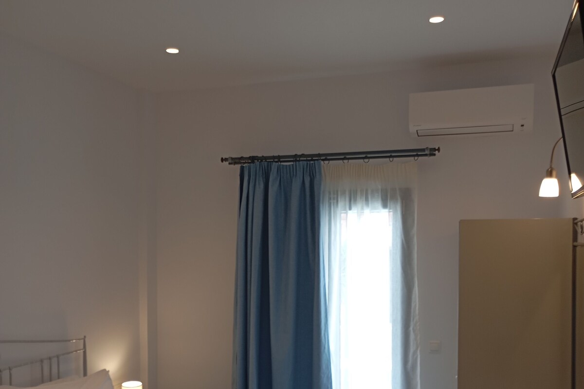 A hotel room with a bed, bedside table, lamp, and a mirror.