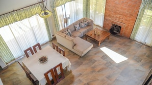 A dining area with a table and chairs, a sofa, and a fireplace. - Vista Del Campo Country Club & Villas Srl (Jarabacoa)