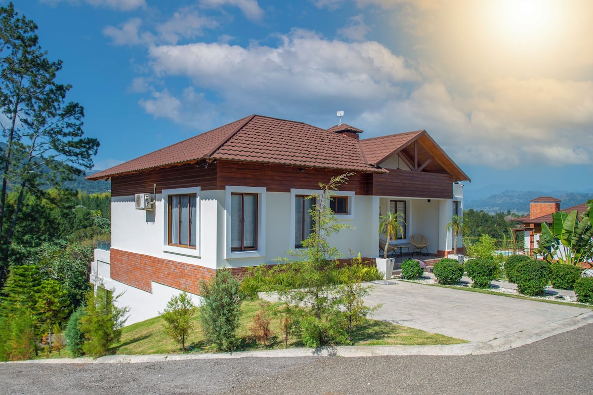 Ein zweistöckiges Haus mit rotem Ziegeldach, weißen Wänden und einer kleinen Veranda.
