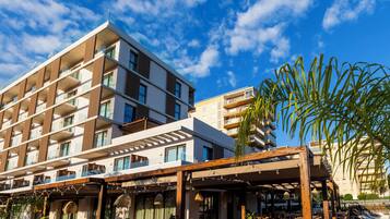 Un hotel de varios pisos con balcones, mobiliario exterior y una zona de piscina.