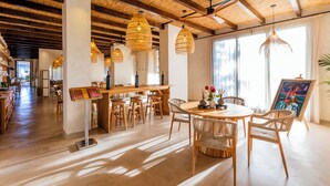 A spacious dining area with a wooden table, wicker chairs, and hanging wicker lamps. - Albades Hotel & Spa (Benicassim)