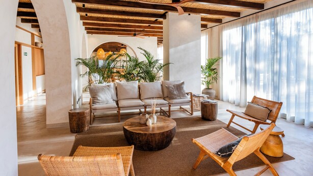 A spacious lounge area with a sofa set, wicker chairs, a coffee table, and large windows with sheer curtains. - Albades Hotel & Spa (Benicassim)