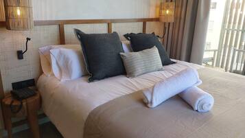 Una cama bien hecha con almohadas, un teléfono en la mesita de noche y una lámpara.