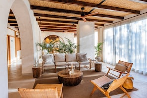 A spacious lounge area with a sofa set, wicker chairs, a coffee table, and large windows with sheer curtains. - Albades Hotel & Spa (Benicassim)