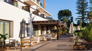 A hotel patio with outdoor seating, a covered area, and a view of the building's exterior. - Albades Hotel & Spa (Benicassim)