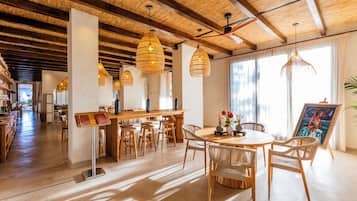 Un comedor amplio con una mesa de madera, sillas de mimbre y lámparas colgantes de mimbre.