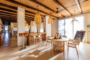A spacious dining area with a wooden table, wicker chairs, and hanging wicker lamps. - Albades Hotel & Spa (Benicassim)