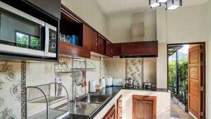 Een moderne keuken met een magnetron, spoelbak en houten kastjes.