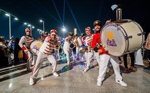 Un grupo de músicos actuando en un escenario con una batería e instrumentos de viento metal.