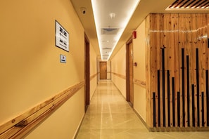A hotel hallway with directional signs, a fire alarm, and a wooden partition. - Pride Hotel Rishikesh (Narendranagar)