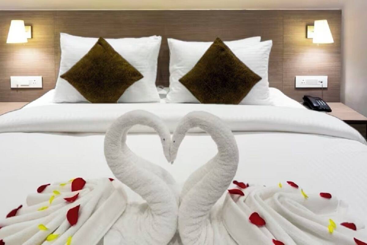 Ein Hotelzimmer mit einem Bett, zwei Nachttischen, einem Telefon und einer herzförmigen Dekoration auf dem Bett.