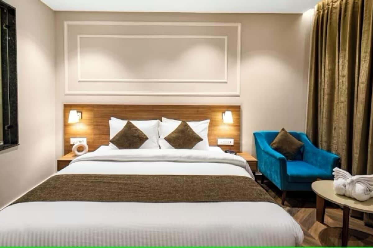 Ein Hotelzimmer mit einem großen Bett, zwei Nachttischlampen, einem blauen Sessel und einem kleinen runden Tisch mit einem Handtuch.