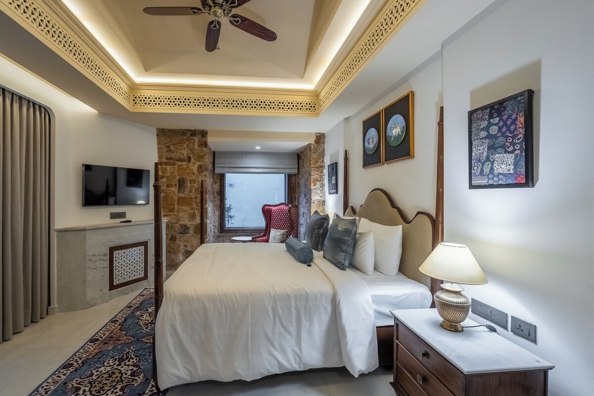 A hotel room with a bed, a TV, a lamp, and a view of the outside.