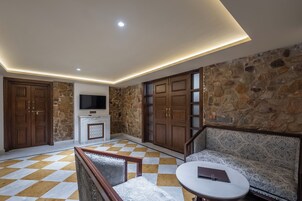 Una habitación con suelo a cuadros, chimenea, televisión y sofá.