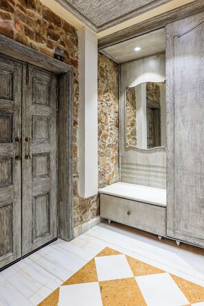 A bathroom with stone walls, a wooden vanity, a mirror, and a checkered floor. - Juna Mahal Jungle Resort (Sawai Madhopur)