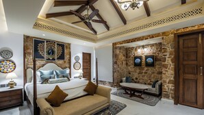 A bedroom with a four-poster bed, a sofa, a dining table, and a stone accent wall.