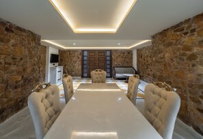 A conference room with a long table, four upholstered chairs, a television, and a piano. - Juna Mahal Jungle Resort (Sawai Madhopur)