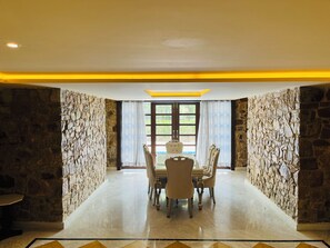 A dining area with a stone wall, a table with chairs, and a view through a window.