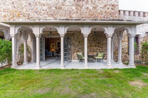 Un edificio de piedra con un patio cubierto que tiene columnas y mesas al aire libre.