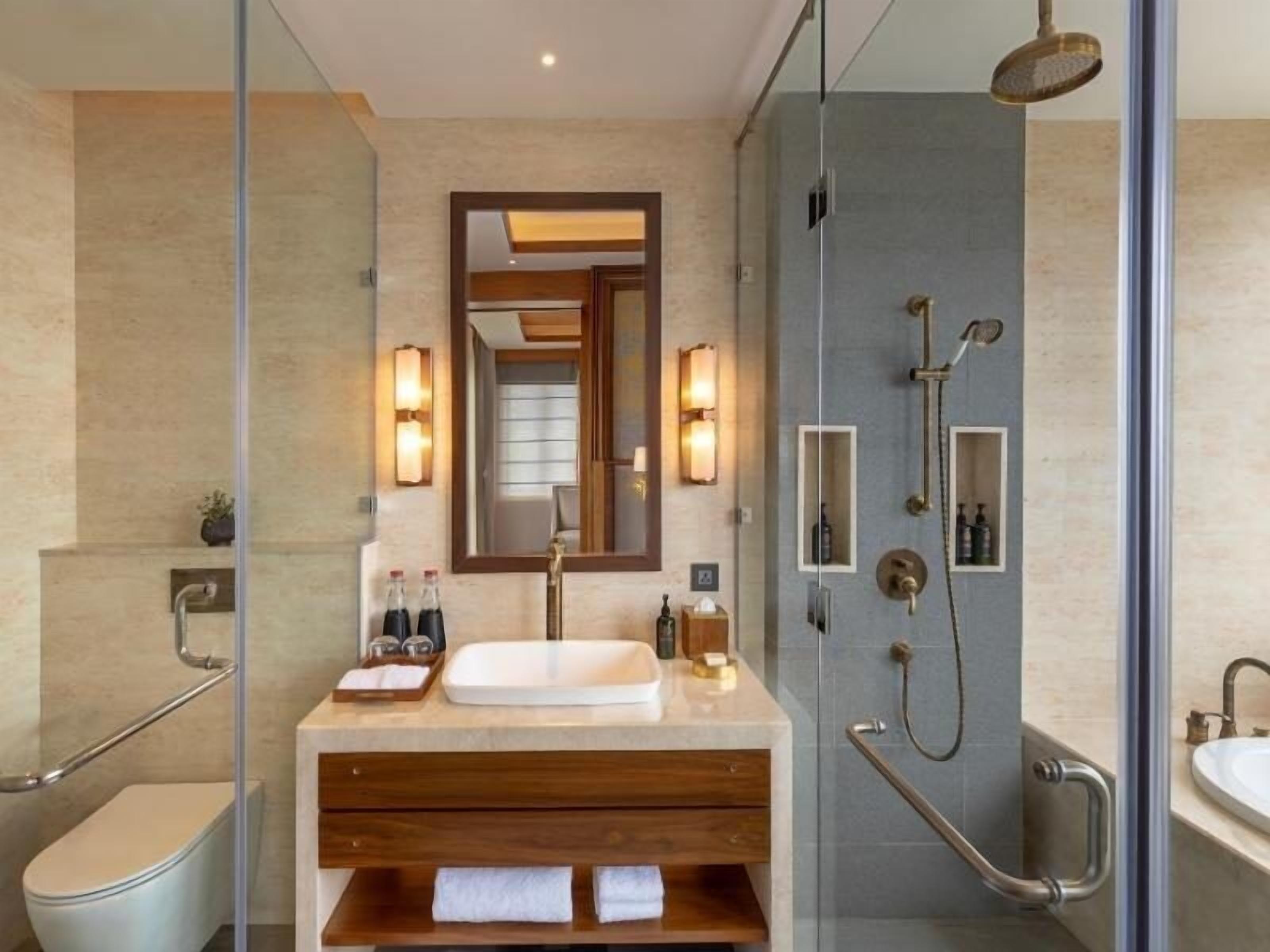 A modern bathroom with a glass-enclosed shower, a wooden vanity, a large mirror, and a toilet.
