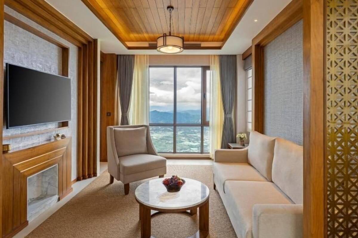 Una sala de estar con televisor, sofá, sillón y un ventanal con vistas.